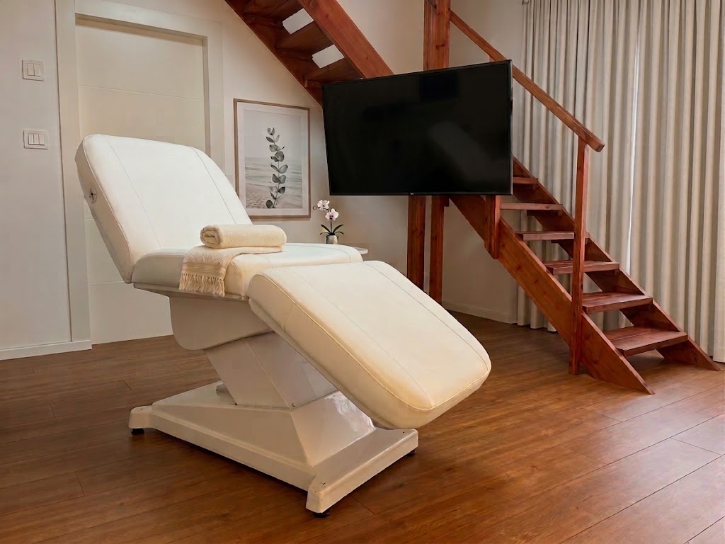 The MBE treatment room — a cream professional treatment bed beside a wooden staircase